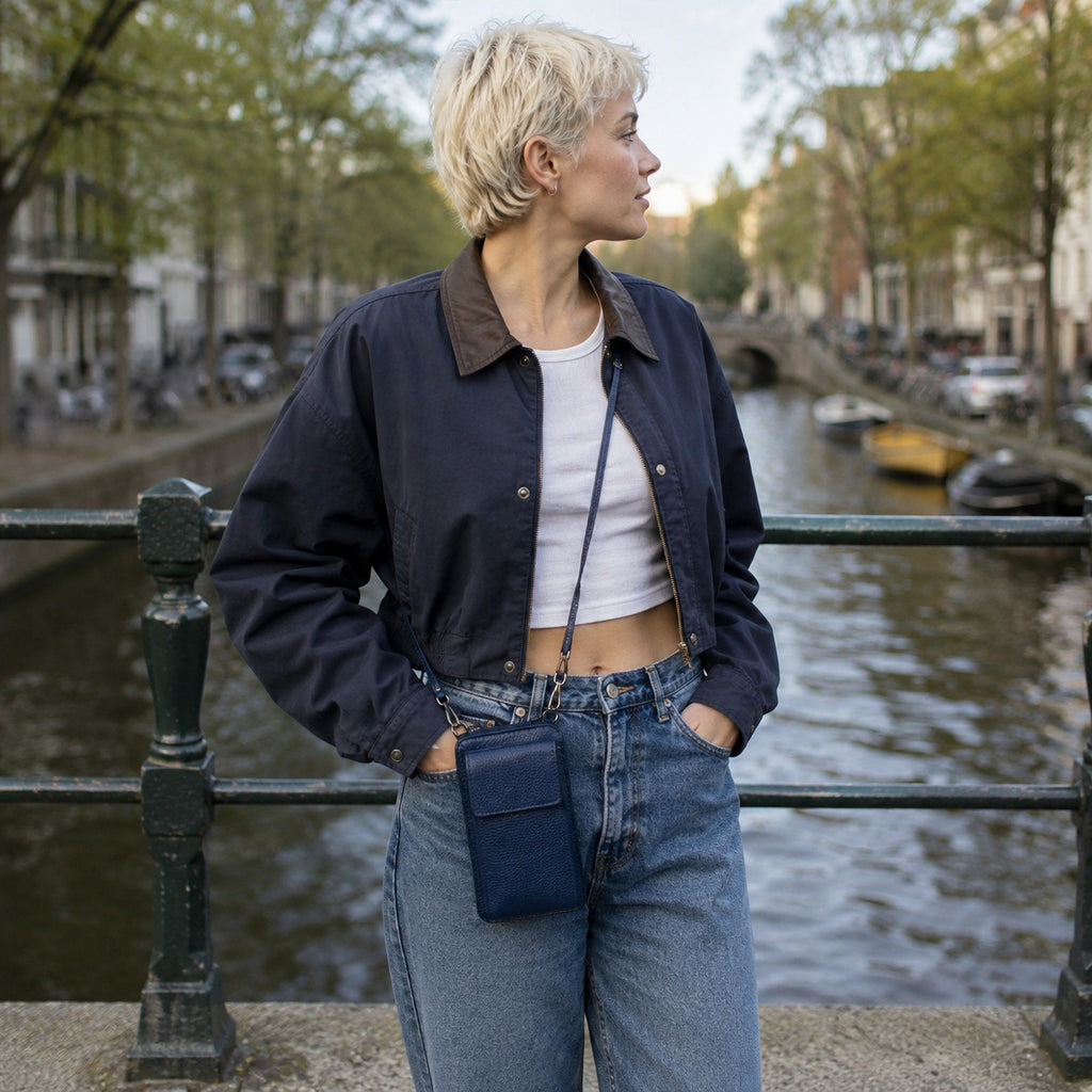 Petite pochette telephone cuir bleu marine portee en croix sur un pont au dessus d un canal