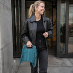 Sac carre daim bleu canard a franges porte a la sortie d un immeuble de bureaux
